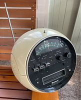 Side view showing cream circular Space Ball design with antenna and front control panel featuring sliders and knobs.