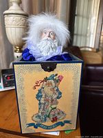 Full view of the closed wooden box with vintage Pere Noel design on the front and Santa figure partially visible topped out of the box