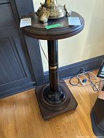 Full view of the Victor Victrola pedestal side table showing round wooden top, black cylindrical column, and square wooden base on hardwood floor.