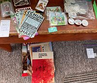 Collection of vintage paper flyers, advertisements, Gulf buttons, CHUM Radio flyers and vintage magazines on wooden table and floor.