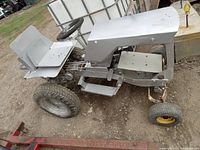 Side view photo of the 1969 Allis Chalmers B10 rolling frame showing the seat, steering wheel, and front and rear tires attached to the silver painted metal frame without engine or accessories.