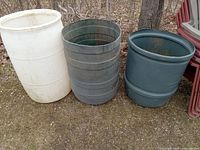 Three large plastic water containers placed outside on the ground, showing overall size, colors, and shapes.