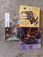 Four puzzle boxes on floor: includes shaped moose jigsaw puzzle box, colorful classic puzzles, and fantasy style puzzle with dragon art