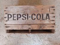 Top view of wooden crate showing 'PEPSI-COLA' stencil lettering.