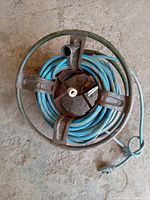 Top-down view of one blue extension cord extended on a green metal reel showing cord thickness and plug type.