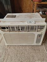 Full view of Haier window air conditioner unit with remote control placed on top.