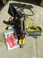 Side view of Radley green and black miter saw with manual and dust collection bag showing handle, blade guard, and power cable.