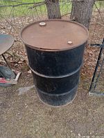 Full side view of the black steel drum showing rust and wear on the surface.