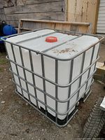 White plastic intermediate bulk container (IBC) water tote in metal cage on molded pallet base with red screw cap