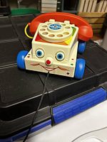 Front view of the vintage Fisher Price Chatter Telephone toy showing the smiling face, rotary dial, and pull cord.
