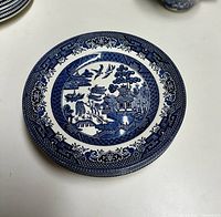 Top view of a stack of 4 Blue Willow salad plates showing the traditional blue and white Willow pattern design.