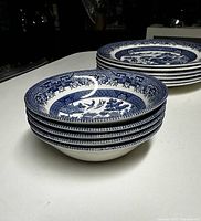 Stack of five Blue Willow pattern ceramic bowls showing rim design and side profile