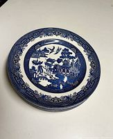 Stack of 6 Blue Willow dinner plates showing the detailed blue and white pattern and size.