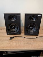Front view of both Alesis Elevate 4 speakers with volume knob and power cord visible on right speaker.