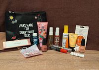 Wide view of all items arranged on brown background with makeup bag behind them.