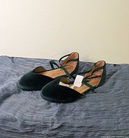 Side and front angled view of the green velvet women's flats showing pointed toe and cross strap details.