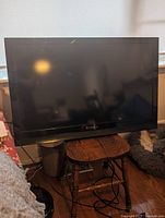 Front view of black-framed Dynex LCD TV showing screen and bezel with minor surface wear.