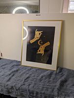 Full view of the gold IKEA frame with black and gold celestial hands print resting on gray cloth.