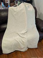 Pair of beige room darkening curtains draped over a chair showing fabric texture and color