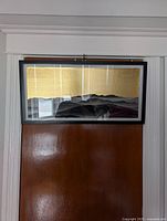 Full view of large horizontal framed art piece hung on door, showcasing mountain-like layers in black and gray and gold textured top section.