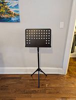 Music stand in standing position, showing perforated sheet holder and tripod base