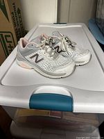 Side view of the pair of used New Balance running shoes showing white and pink mesh, synthetic material and laces