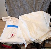 Two queen size white flat sheets stacked and slightly folded with one sheet showing a red Endy tag.