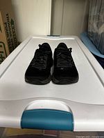 Front view of the black New Balance shoes placed side by side, showing the laces and toe areas.