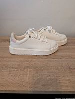 Side view of white platform sneaker showing thick sole and smooth upper with lace