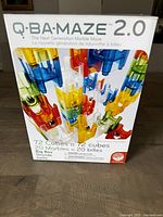 Front of Q-BA-Maze 2.0 Big Box packaging showing product information and colorful cubes forming maze towers.