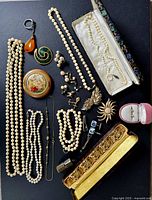 Overhead arrangement of all jewelry pieces and compact on black background