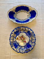Top view of the oval serving dish and round plate placed on a light linen cloth to show design and colors
