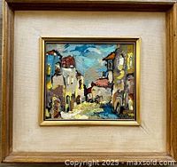 Frontal photo showing the painting of an Israeli street scene with buildings and sky, colorful with textured brush strokes, in a wooden frame with fabric matting.