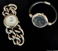 Two stylish ladies wristwatches on a black background, showing Visage with silver chunky chain bracelet and Labrea with black strap and black dial.