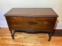 Front view of the walnut chest showing the smooth top with carved edge detail and raised panel on the front face.