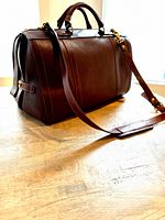 Front and side view of the brown leather weekender bag with top handles and shoulder strap