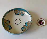 Top view of decorative bowl and miniature plate showing blue background and gold accents on bowl, floral motif on plate