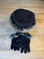 Black ladies hat with fur trim and matching gloves on wooden surface.