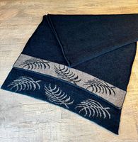 Folded black and grey shawl showing fern pattern detail on edge.
