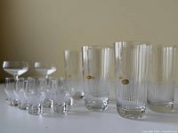Photo showing six tall Rosenthal drinking glasses with vertical etched lines and gold labels, eight smaller liqueur glasses, and two small stem glasses arranged on a flat surface.