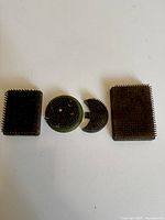 Four Kenzan flower frogs displayed in a row showing their tops with metal spikes, including rectangular and circular forms.