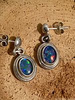 front view of sterling silver fire opal earrings showing oval cabochons and dangle design
