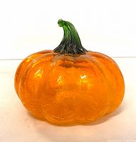 Front view of orange crackle glass pumpkin showing green stem