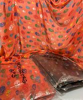 Orange sample scarf draped, packages labelled 10 pcs orange and black visible