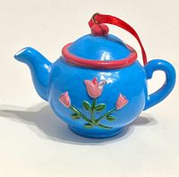Side view of blue teapot ornament showing tulip design and ribbon