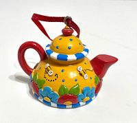 Side view of miniature teapot ornament with hanger showing colors and design