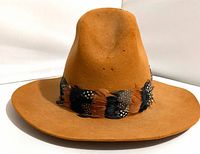 Front view showing tan felt hat, feather hatband, holes on crown
