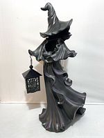 Full view of witch figure holding lantern