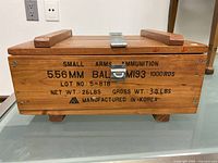 Closed front view showing the wood exterior with printed text including caliber 5.56mm, model M193, capacity 1000 rounds, weight and Made in Korea markings.