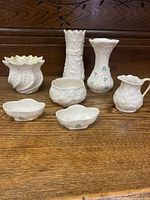 Full view of all seven pieces in the ceramic set on a wooden surface, showing vases, bowls, dishes, and pitcher with shamrock and floral designs.